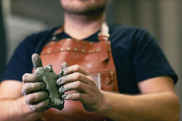 Pematung memakai celemek kulit dengan tanah liat di tangan. Workshop pembuatan kerajinan patung — Stok Foto
