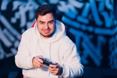 Genç adam oyun konsolunda oyun platformunda oturuyor.