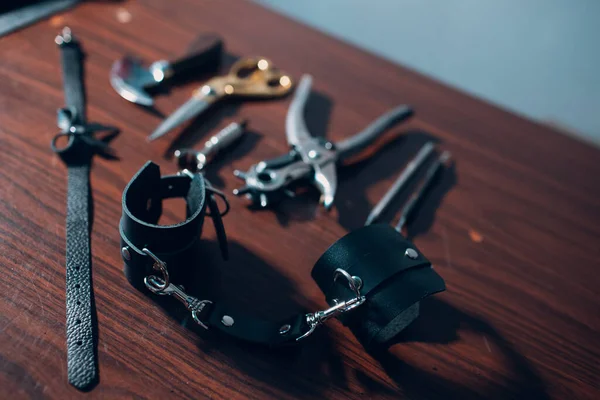 Таннерні інструменти та шкіряні наручники на столі — стокове фото