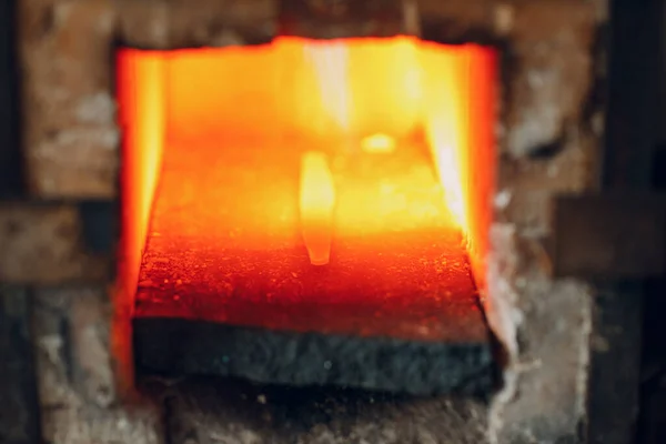 Blacksmith menempa oven dengan api panas. Smith memanaskan besi baja dalam api tempa panas Stok Foto