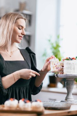 Pasta şefi, mutfak masasında pastası olan beyaz bir kadın..