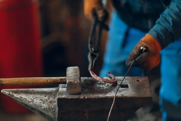 Pandai besi menempa dan membuat detail logam dengan palu dan landasan di menempa — Stok Foto