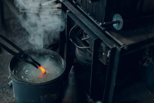 Fucine da fabbro e ferro di cavallo in metallo temperato in vaso con acqua alla fucina — Foto Stock