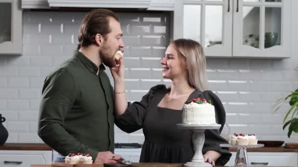 糕点师糕点师年轻的高加索女人与丈夫男友男人尝试在厨房桌上品尝蛋糕。蛋糕、蛋糕和甜食. — 图库视频影像