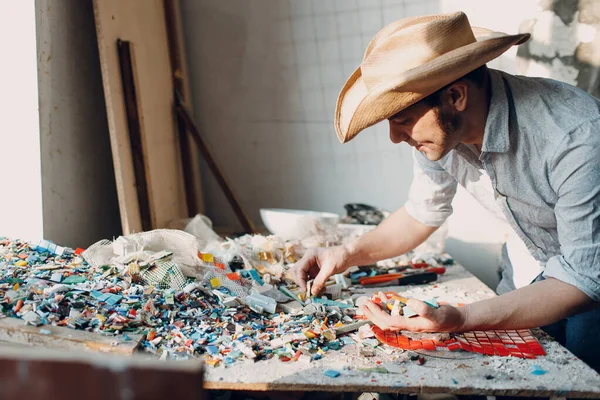 Master mosaik pria memilih potongan kaca smalt untuk panel mosaik. Pria mosaicist di tempat kerja. — Stok Foto