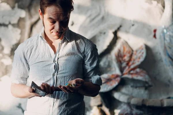 Pengrajin laki-laki master potret memegang palu dan kaca smalt potongan di lengan untuk karya seni mosaik di bengkel — Stok Foto