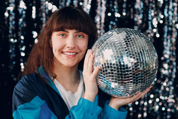 Wanita muda dengan gaya 80 dan 90-an. 90s fashion positif gadis di pesta disko dengan bola disko di tangan. — Stok Foto