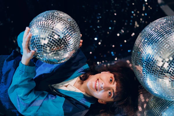 Wanita muda dengan gaya 80 dan 90-an. 90s fashion positive girl at night club disco party with disco ball. Stok Gambar Bebas Royalti