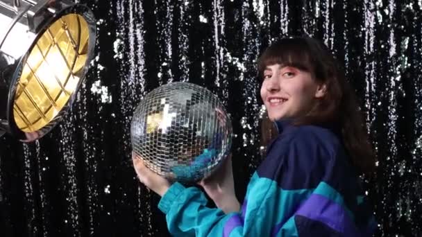 Молода спортивна жінка 80 і 90-х років. 90-ті мода позитивна дівчина на диско-вечірці з диско м'ячем в руках . — стокове відео