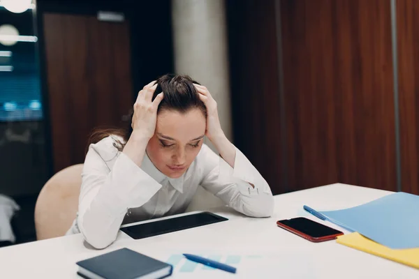 Pengusaha wanita sedih duduk dan memegang kepala dengan tangannya di meja kantor. Bisnis wanita sakit kepala dalam krisis dan depresi setelah covid-19 pandemia konsep — Stok Foto