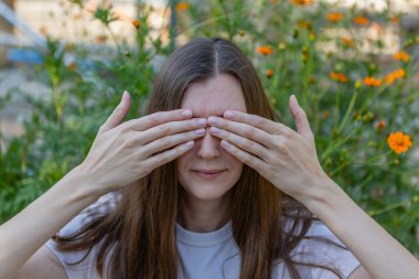 A woman covers her eyes with her hands.
