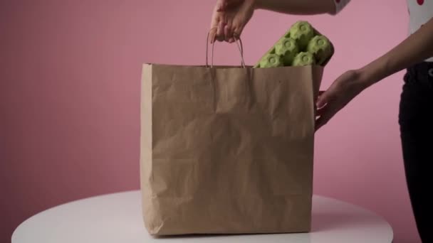 Mujer Pone Una Bolsa Comestibles Sobre Mesa Sobre Fondo Rosa — Vídeo de stock