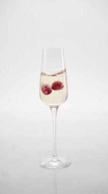 Yakın plan: çilekler bir kadeh şampanyaya düşer.