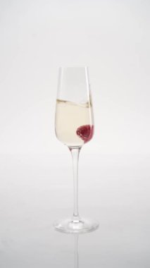 Yakın plan: çilekler bir kadeh şampanyaya düşer.