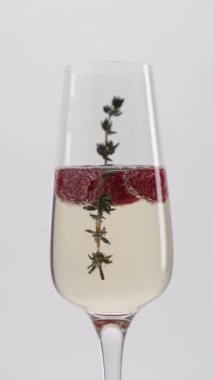 Yakın plan: Bir bardak çilekli köpüklü şampanya içinde biberiye filizi.