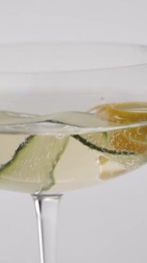 Yakın plan: salatalıklı, köpüklü bir şampanya kadehinde limon.