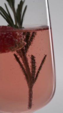 Yakın plan: Bir bardak çilekli köpüklü şampanya içinde biberiye filizi.