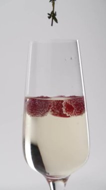 Yakın plan: çilekler bir kadeh şampanyaya düşer.