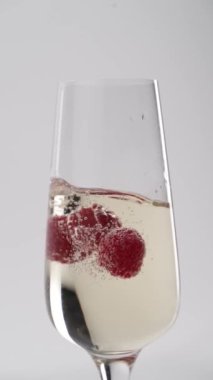 Yakın plan: çilekler bir kadeh şampanyaya düşer.