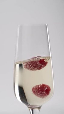 Yakın plan: çilekler bir kadeh şampanyaya düşer.