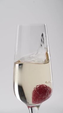 Yakın plan: çilekler bir kadeh şampanyaya düşer.