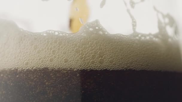 在杯子中以慢动作倒入气泡的深色啤酒 — 图库视频影像