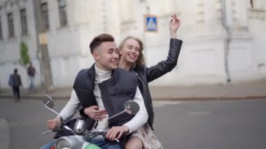 Evli bir çift şehirde motosiklet sürüyor.