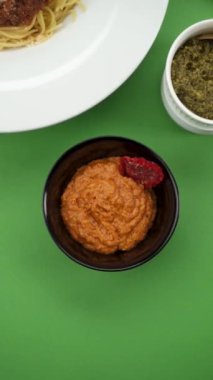 Yeşil arka planda bir tabakta pesto sosu.
