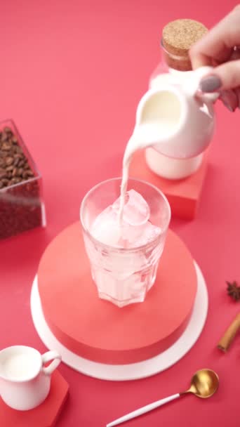 Wlewanie Mleka Szklanki Lodem Różowym Tle — Wideo stockowe