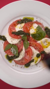 Domatesli Mozzarella kırmızı arkaplanda bir tabakta döner.