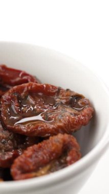 Beyaz arka planda kırmızı tabakta kurutulmuş domatesler.