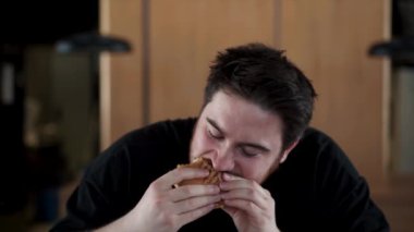 Çılgın inek zevkle lezzetli bir burger yer, sos dudaklarına akar.