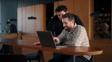 Genç bir bilişim uzmanı proje hakkında yönetmenle iletişim kuruyor, çalışmanın sonuçlarını gösteriyor.