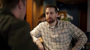 Barda oturmuş sohbet eden iki adam.