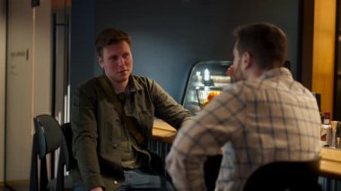 Barda oturmuş sohbet eden iki adam.