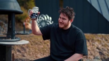 A man drinks beer in nature near the barbecue