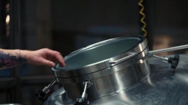 Bir adam bira fabrikasında sarnıç açıyor.