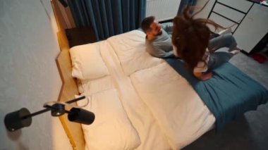 young couple in hotel room fall on bed for the first time