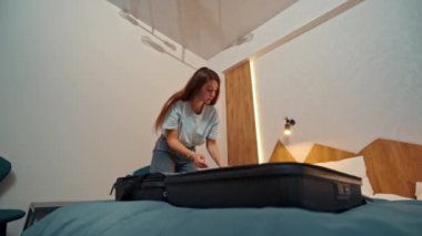 Genç bir kız giysilerini bavuldan çıkarıyor.