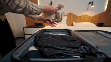 a young man takes out his clothes from a suitcase