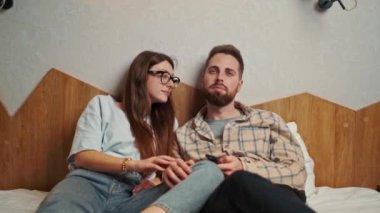 young couple watching TV in hotel room calmly