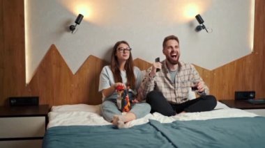 young couple watching football in hotel room with chips