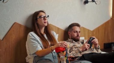 Genç çift otel odasında televizyon izliyor ve gülümsüyor.