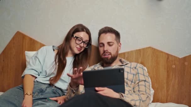 一对年轻夫妇在酒店房间里观看平板电脑上的视频 面带微笑 — 图库视频影像