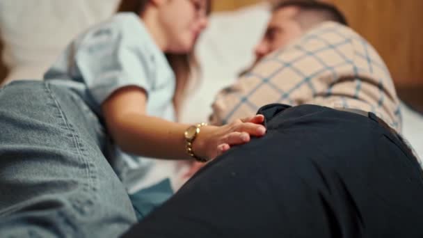 一对年轻夫妇躺在旅馆房间的床上 彼此爱抚着对方 — 图库视频影像