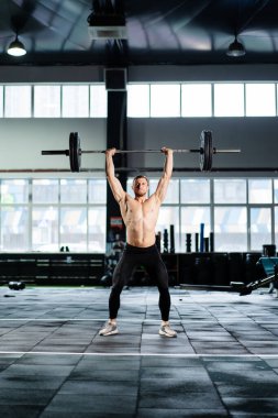 Atletik adam sert spor salonunda halter presi yapıyor.