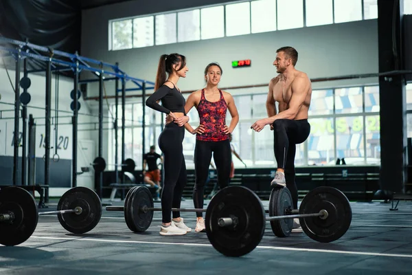 Atletik sporcu erkek sporcu, sıkı spor salonundaki eğitiminden sonra formda kızlarla iletişim kurar. Sağlıklı erkek ve kadın beden eğitimi egzersizinden sonra yoruldu..