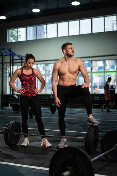 Yorgun erkekler ve kadınlar spor salonundaki yoğun egzersizden sonra dinleniyorlar. Spor salonundaki antrenmandan sonra sağlıklı erkek ve kadın yorulmuştu. Yorgun erkek ve dişi yoğun egzersizden sonra ayakta ve dinleniyor..
