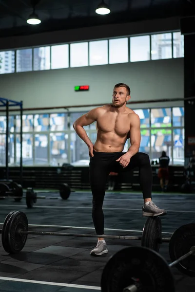 Spor salonundaki yoğun egzersizden sonra yorgun gençler dinleniyor. Spor salonundaki antrenmandan sonra yorgun ve sağlıklı bir adam. Yorgun erkek model, yoğun egzersizden sonra ayakta duruyor ve dinleniyor..