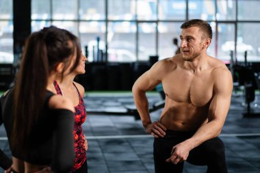 Atletik sporcu erkek sporcu, sıkı spor salonundaki eğitiminden sonra formda kızlarla iletişim kurar. Sağlıklı erkek ve kadın beden eğitimi egzersizinden sonra yoruldu..